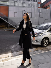 a lady wears a black trench coat  with black pants